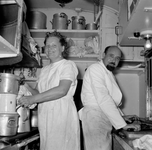 836803 Afbeelding van een kok en een kokkin in de keuken van het restauratierijtuig van de Hotelplan Expres van Den ...